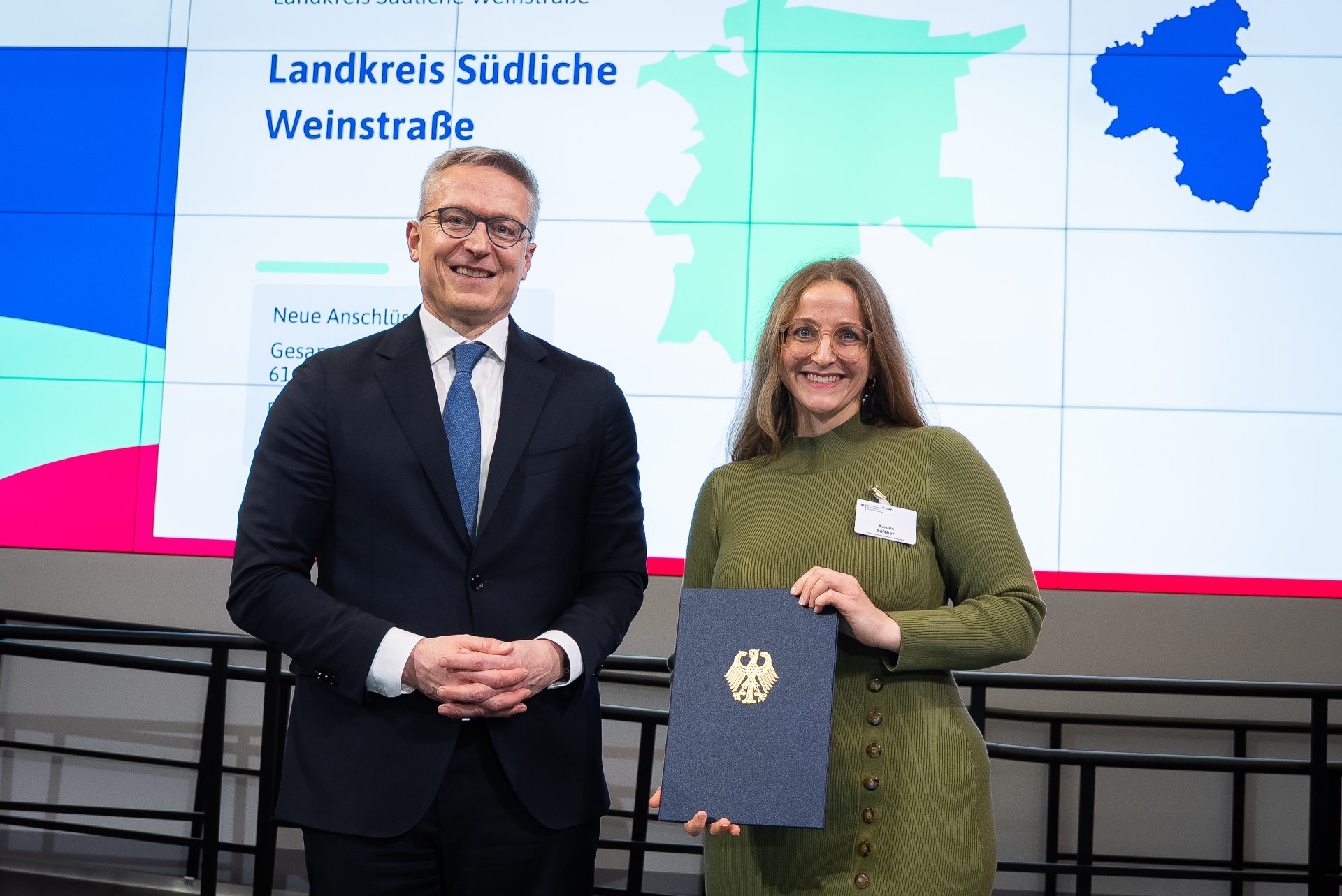 Symbolische Übergabe des Förderbescheids zur Gigabitförderung: Vertreter des Bundes überreicht die Förderung an Vertreterin des Landkreises Südliche Weinstraße.