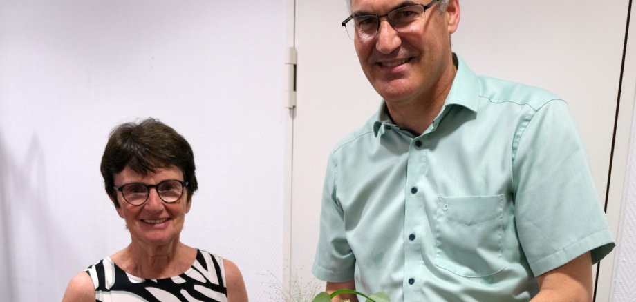 Eine Frau und ein Mann in festlicher Kleidung, er übergibt ihr einen Blumenstrauß.