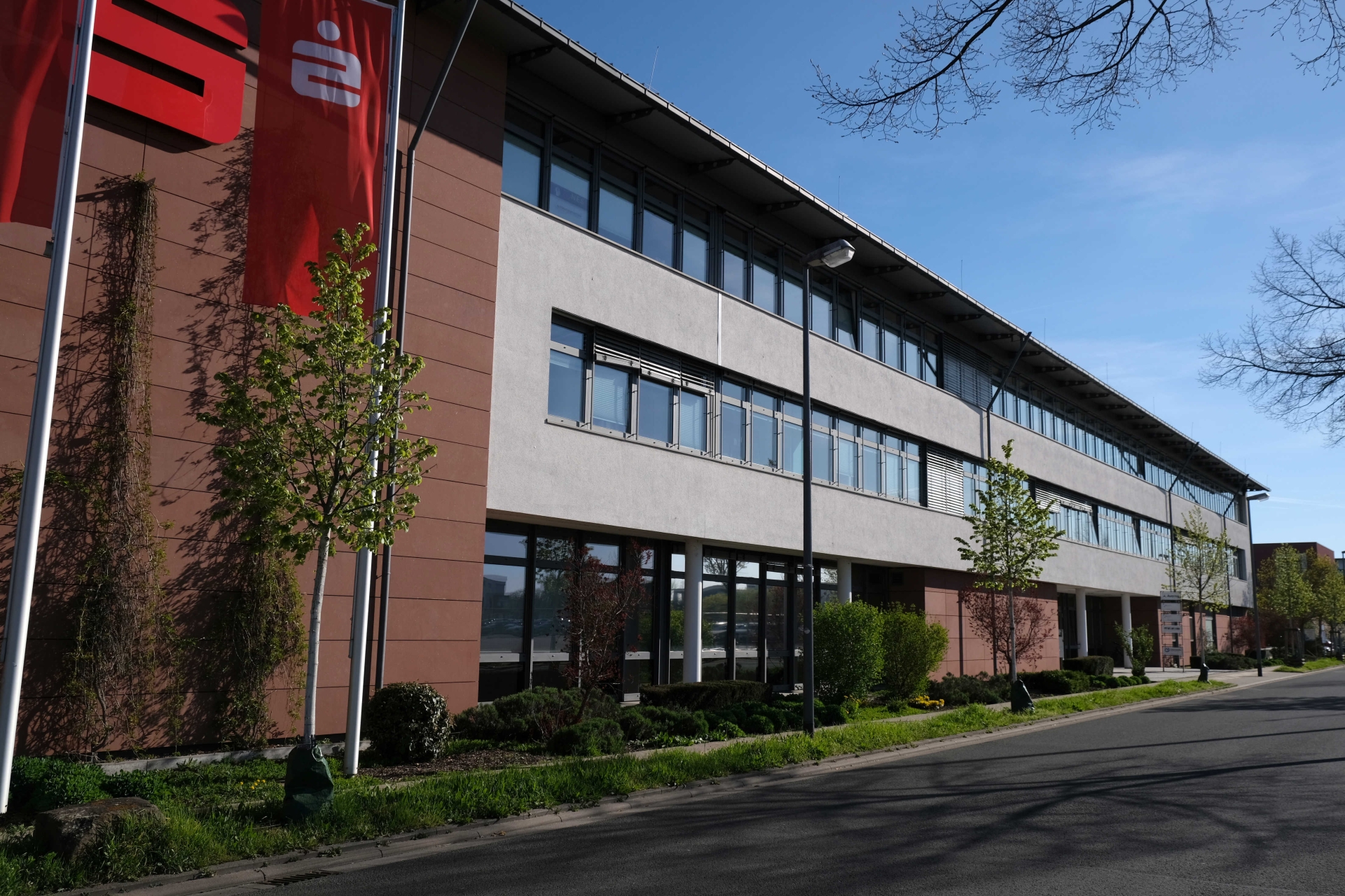Langliches Bürogebäude, am Rand Sparkassen-Logo und -Flagge.