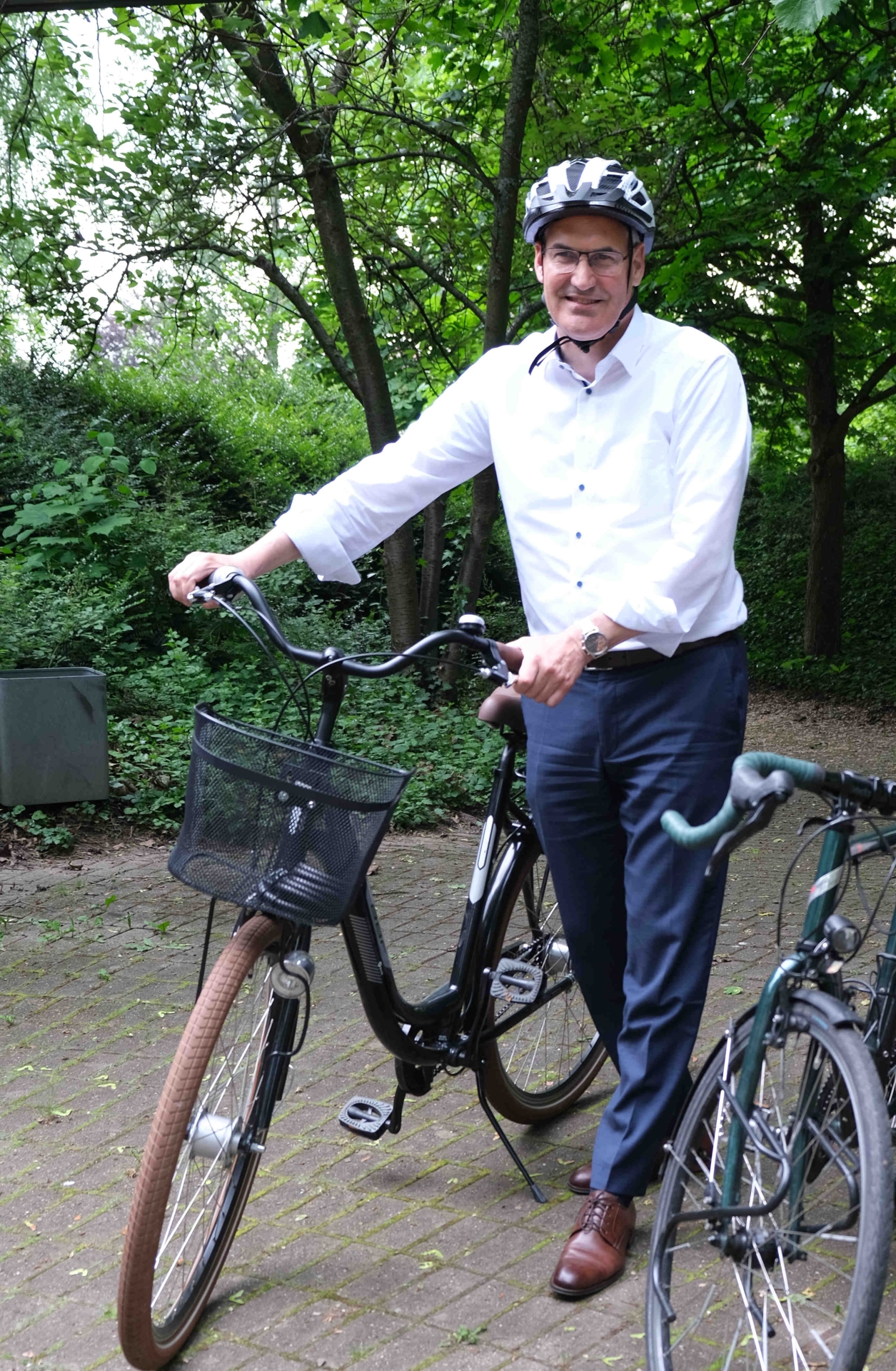 Dietmar Seefeldt neben einem Fahrrad, trägt Helm, im Hintergrund Weinreben.