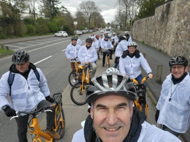 Selfie von Dietmar Seefeldt, er im Vordergrund mit Helm weitere Menschen auf Fahrrädern im Hintergrund. Alla tragen weiße Jacken.