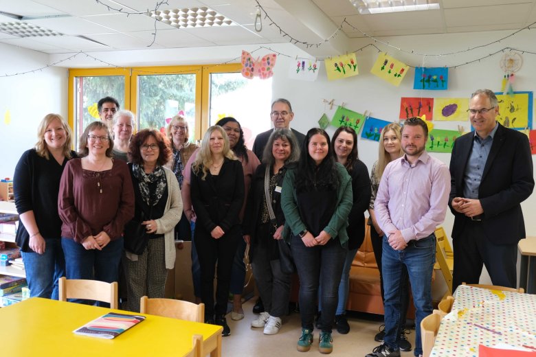 Gruppenbild mit Erwachsenen in einem bunt dekorierten Kita-Raum.