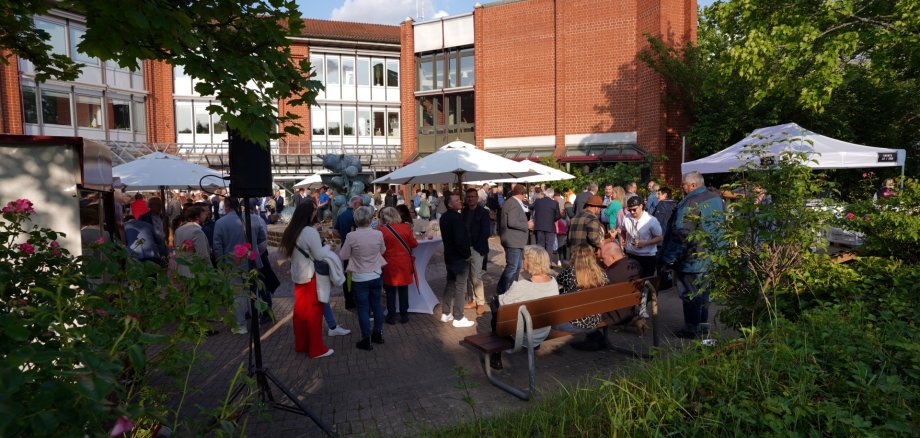 Der Kreisempfang ist gute Tradition im Landkreis Südliche Weinstraße. Archivfoto: KV SÜW Eine Outdoor-Veranstaltung auf dem Platz vor dem Kreishaus der Kreisverwaltung Südliche Weinstraße. Menschen stehen unter weißen Sonnenschirmen vor dem roten Backsteingebäude der Kreisverwaltung. Das Wetter ist sonnig und die Veranstaltung ist gut besucht, mit einer vielfältigen Gruppe von Menschen, die sich unterhalten und das Event genießen.