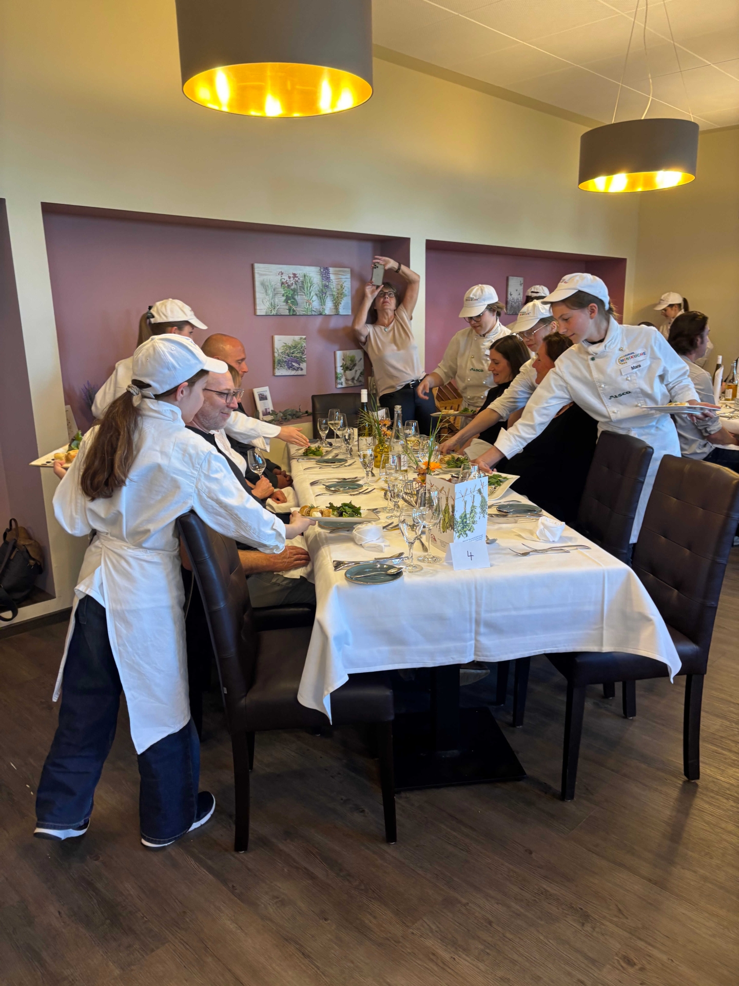 Kinder mit weißen Schürzen und Hochmützen servieren Gerichte.