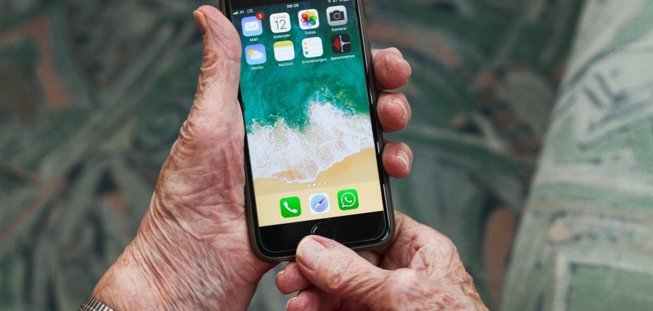 Woche der Medienkompetenz. Symbolbild. Pixabay Ältere Person hält ein Smartphone in beiden Händen und bedient den Home-Button. Auf dem Bildschirm sind verschiedene Apps wie E-Mail, Kalender, Kamera und WhatsApp zu sehen. Der Hintergrund ist unscharf.
