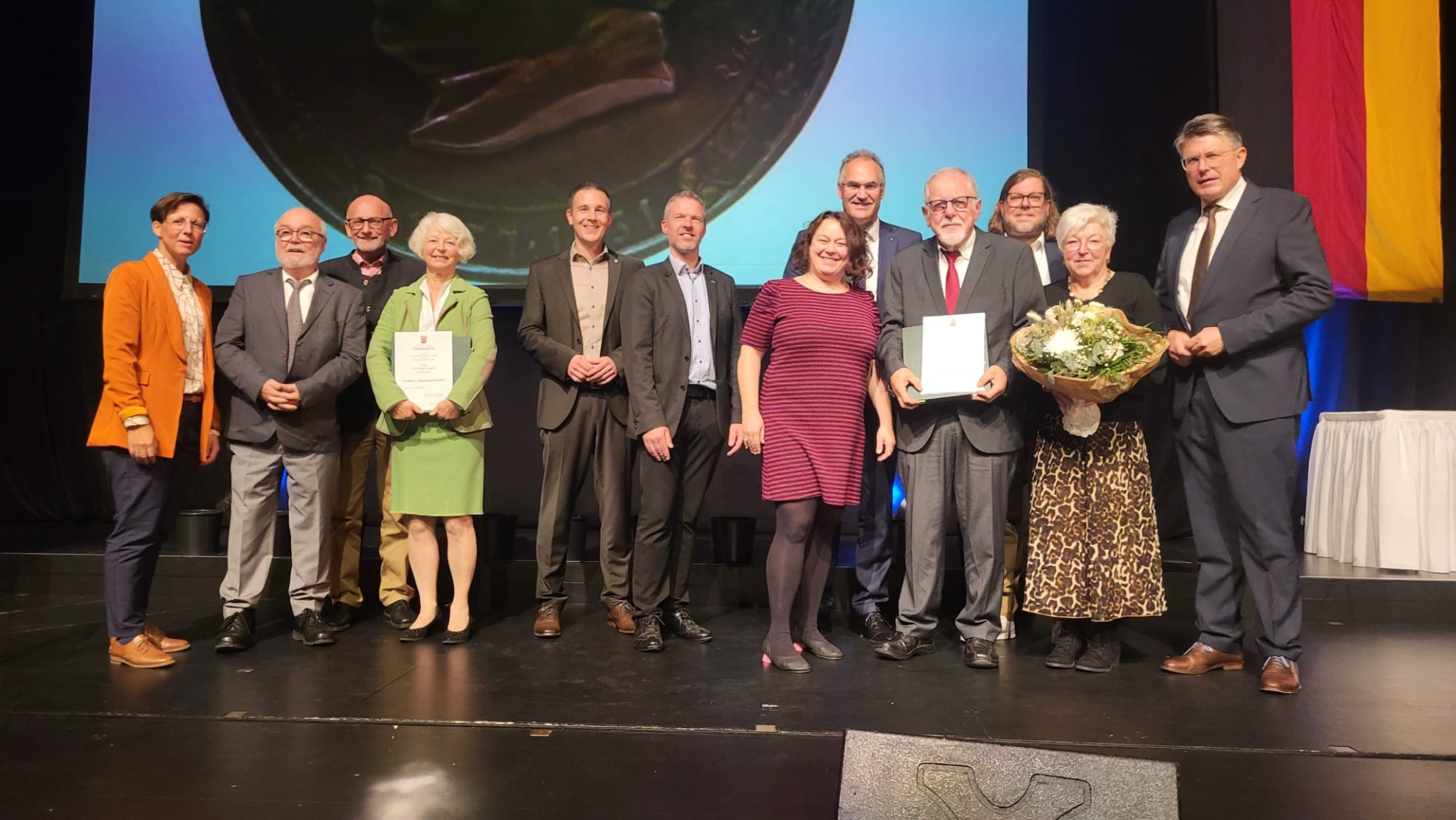 Gruppenfoto von elf Personen auf einer Bühne bei einer feierlichen Ehrung.