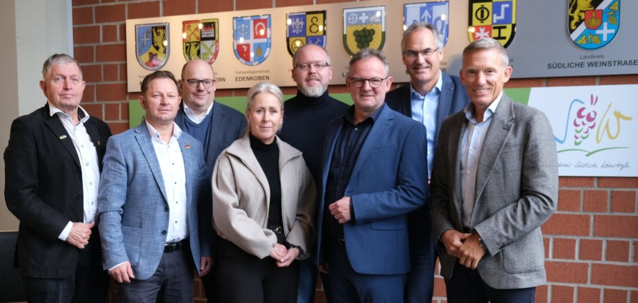 Mitglieder des Finanzausschusses des Landkreistags Rheinland-Pfalz im Kreishaus SÜW, von rechts: Ralf Leßmeister, Landrat Kreis Kaiserslautern, Dietmar Seefeldt, Landrat Kreis SÜW, Stefan Metzdorf, Landrat Kreis Trier-Saarburg, Steffen Wolf, Erster Kreisbeigeordneter Kreis Mainz-Bingen, Dr. Susanne Ganster, Landrätin Kreis Südwestpfalz, Jürgen Hesch, Beigeordneter Landkreistag Rheinland-Pfalz, Konstantin Sawin, Kreistagsmitglied, und Heribert Erbes, Kreistagsmitglied. Foto: KV SÜW Personen stehen vor einer Wand mit Wappen aus dem Landkreis Südliche Weinstraße.