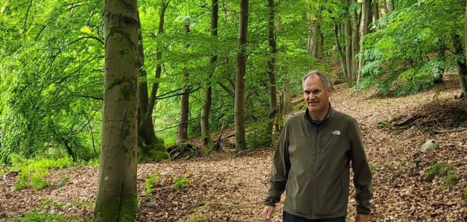 Dietmar Seefeldt auf einem Waldweg, grüne Bäume im Hintergrund.