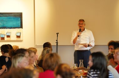 Landrat Dietmar Seefeldt steht mit einem MIkrrofon vor den Gästen einer Veranstaltung und hält eine Ansprache.
