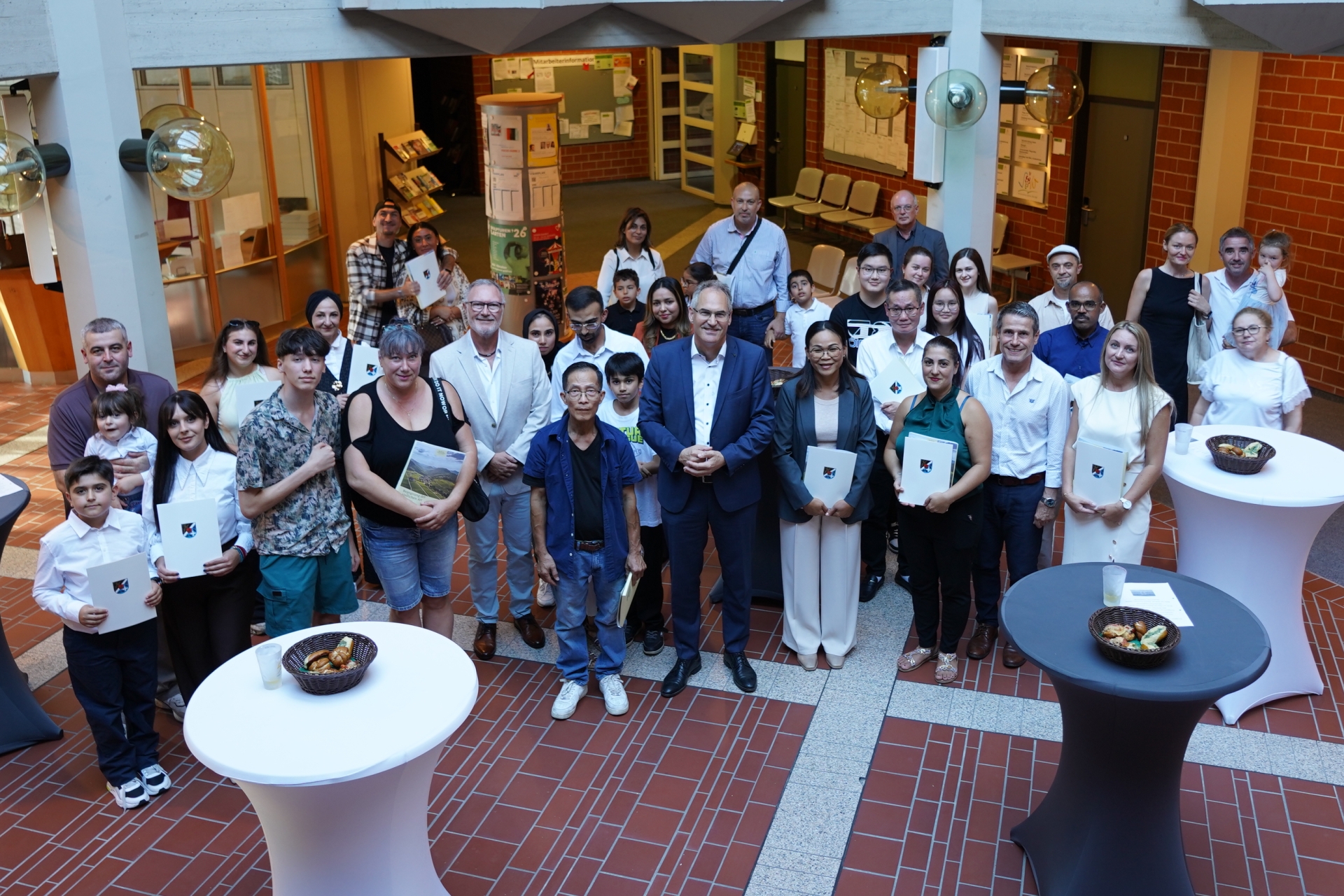 Eine größere Gruppe von Erwachsenen und Kindern steht für ein Gruppenfoto im Foyer der Kreisverwaltung. Mehrere Personen halten Urkunden in den Händen.