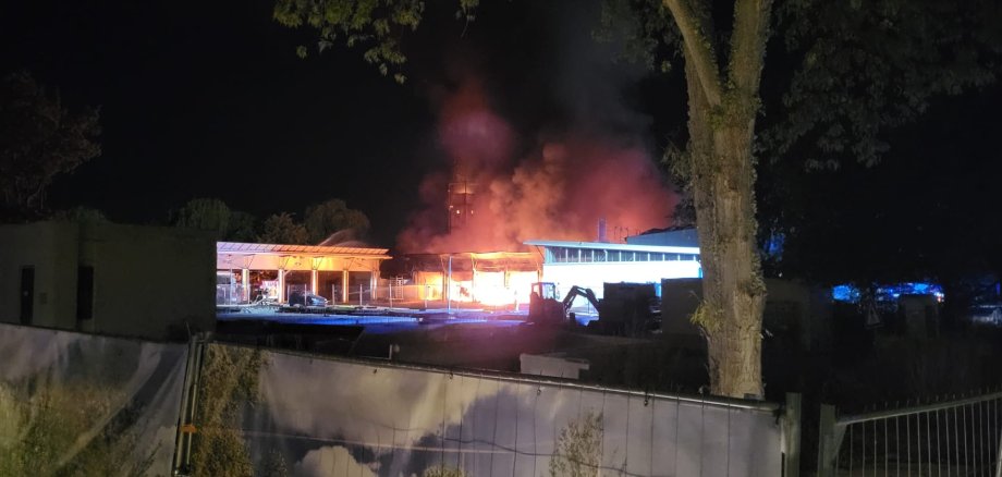 Flammen schlagen aus einer Fahrzeughalle.
