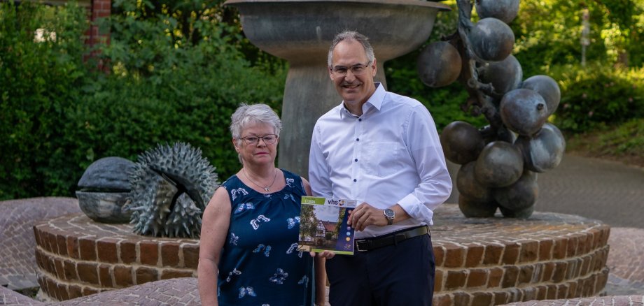 Judith Hammer und Landrat Dietmar Seefeldt stehen gemeinsam am Brunnen vor dem Kreishaus in Landau.
