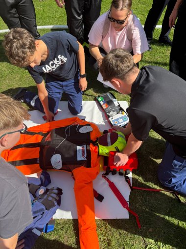 Teamarbeit war beim Jugendfeuerwehr-Wettbewerb in Oświęcim gefragt: An verschiedenen Stationen stellten die Jugendlichen ihr Können und Geschick bei feuerwehr- und rettungsdienstbezogenen Aufgaben unter Beweis. Foto: KV SÜW Mehrere Jugendliche üben auf einer Wiese gemeinsam die Versorgung einer verletzten Person mit Rettungs- und Erste-Hilf-Ausrüstung.