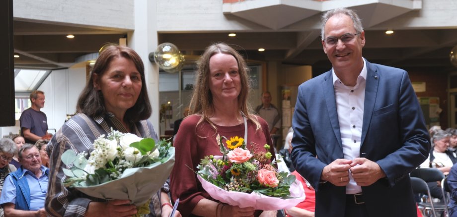Bei der Vernissage im Kreishaus: Natascha Brändli (Mitte) mit Barbara Auer, ehemalige Direktorin des Kunstvereins Ludwigshafen, und Landrat Dietmar Seefeldt. Foto: KV SÜW Zwei Frauen mit Blumensträußen stehen gemeinsam mit Landrat Dietmar Seefeldt im Foyer der Kreisverwaltung.