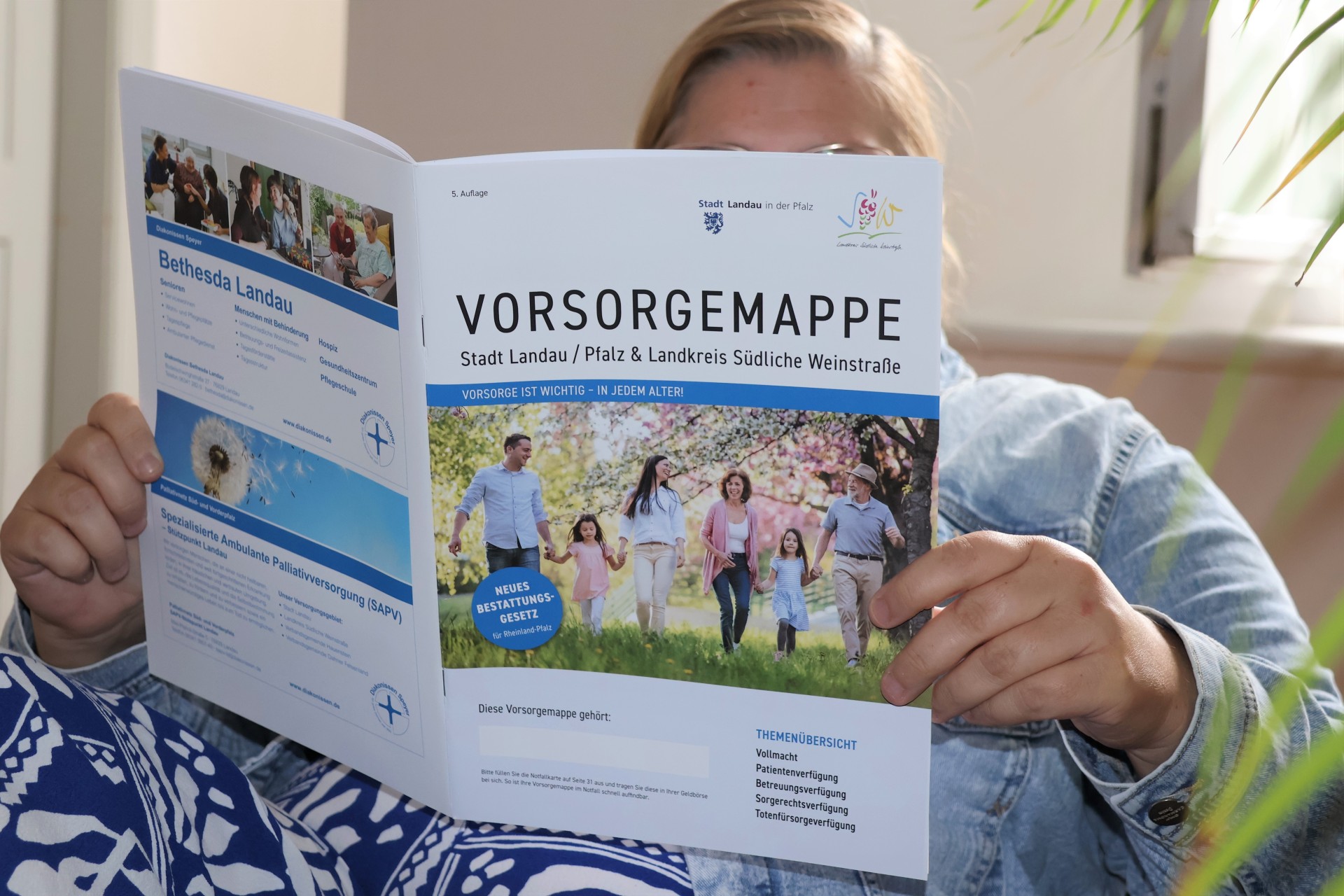 Eine Person hält eine aufgeklappte Vorsorgemappe der Stadt Landau und Landkreises Südliche Weinstraße in die Kamera.
