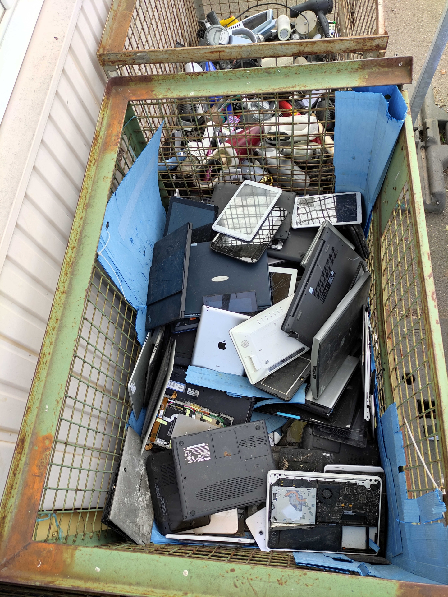 Elektroschrott wie alte Laptops und Tablets liegen gesammelt in einer großen Kiste.