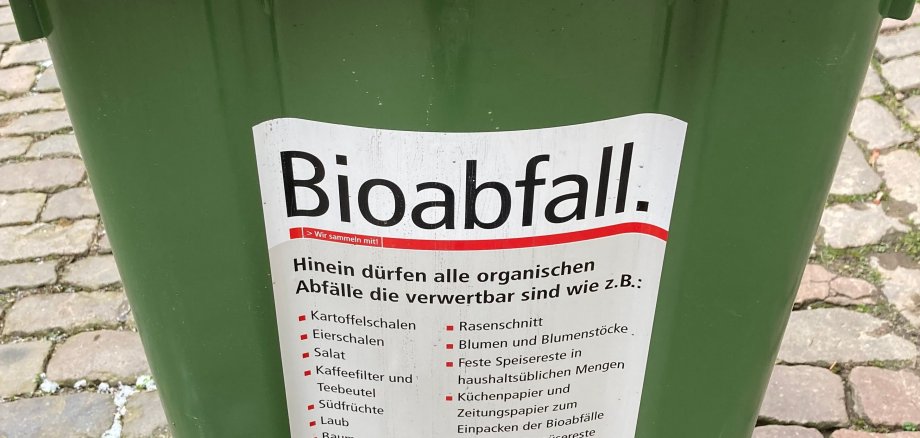 Nahaufnahme einer Biomülltonne. Ein Aufkleber listet die Abfallarten auf, die in der Tonne entsorgt werden dürfen. 