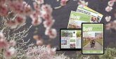 Vor einer Frühlingslandschaft mit blühenden Mandelbäumen sind gedruckte und digitale Ausgaben des SÜW Journals zu sehen. Die Zeitschrift wird auf Papier, als Tablet-Version und als Laptop-Ansicht dargestellt. Die Titelseite zeigt eine Familie, die einen von blühenden Bäumen gesäumten Weg entlanggeht.