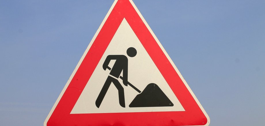 Ein Baustellenschild vor einem blauen Himmel.