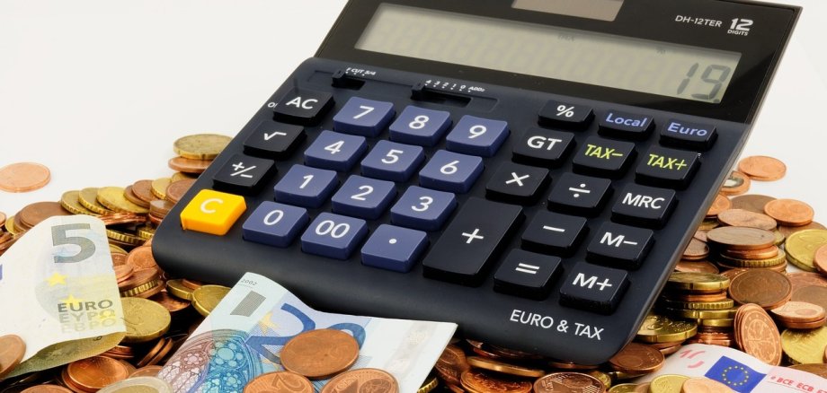 Ein Taschenrechner, Münzen und Geldscheine. 