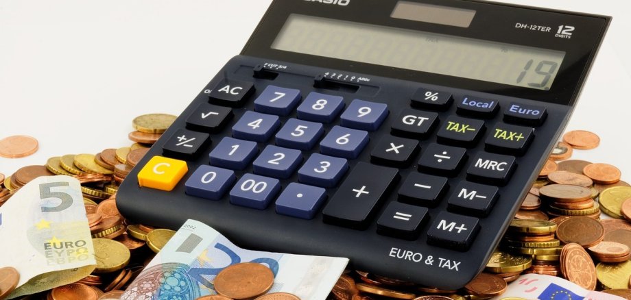 Ein Taschenrechner, Münzen und Geldscheine. 