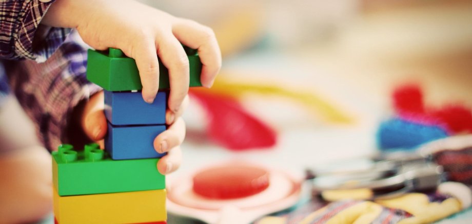 Kinderhände, die mit Bauklötzen spielen.