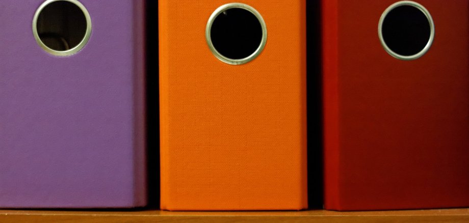 Drei Ordnerrücken von verschiedenfarbigen Aktenordnern.