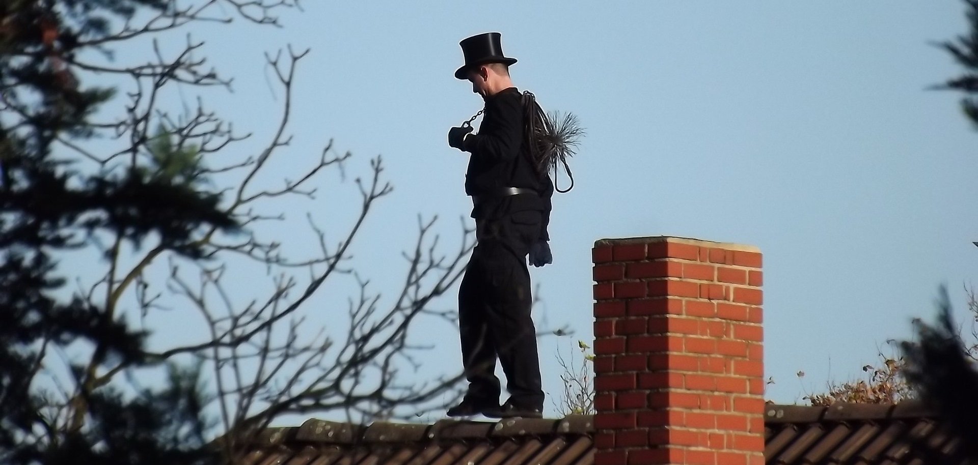 Ein Schornsteinfeger läuft auf einem Dach.