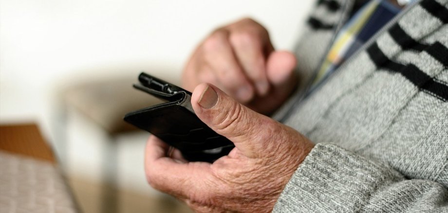 Eine männliche Hand mit einem Smartphone in der Hand. 