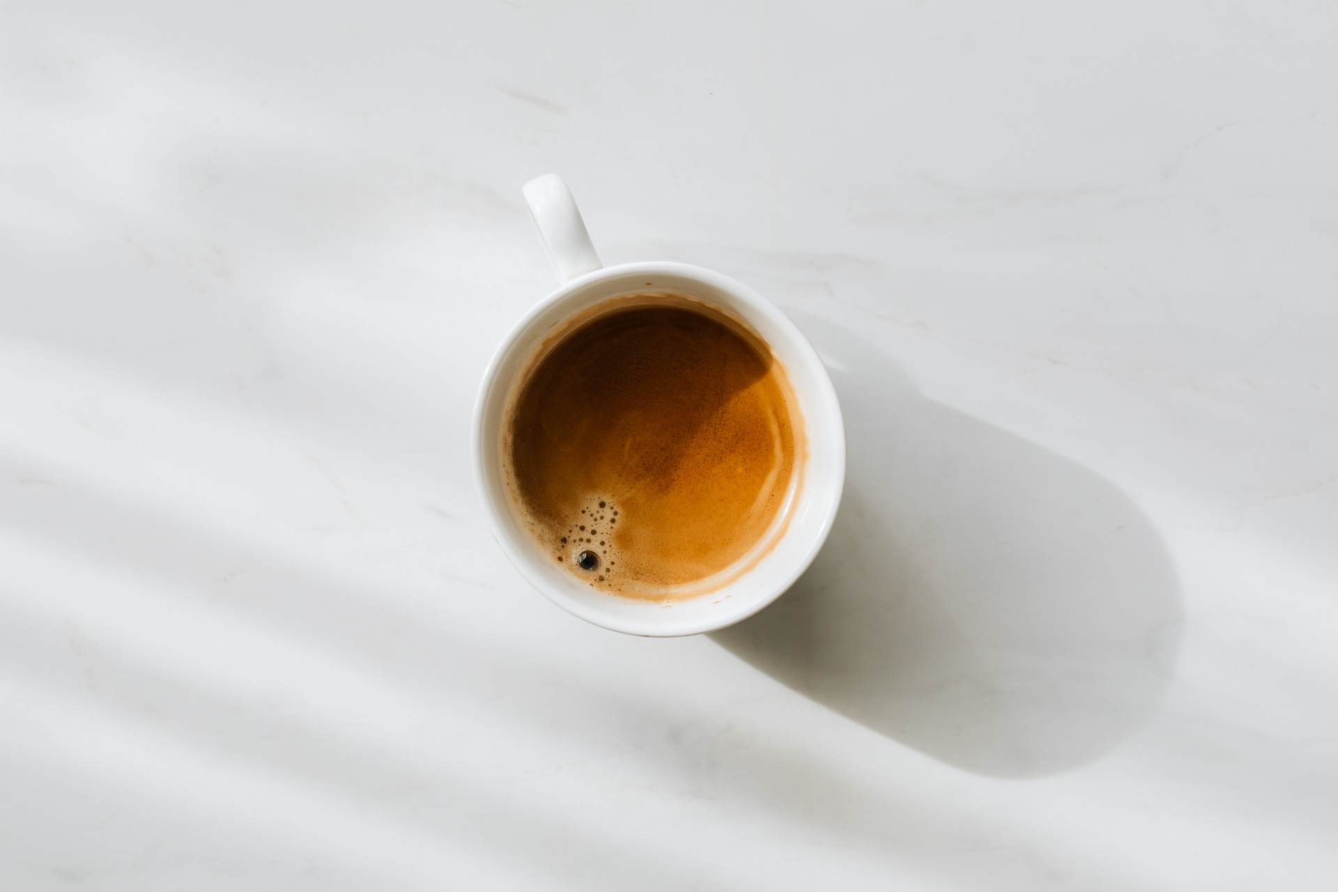 Eine Tasse mit Kaffee, von oben fotografiert. Auf weißem Boden. Foto: yousafbhutta via Pixaby