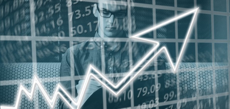 Ein Mann mit Brille blickt auf Unterlagen, ein Pfeil zeigt nach oben. 