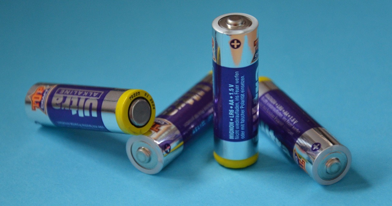 Am 18. Februar ist Internationaler Tag der Batterie. Symbolfoto: Pixabay Mehrere lose AA-Batterien liegen auf einer hellblauen Fläche. Die Batterien sind silber-blau gestaltet, einige liegen seitlich, eine steht aufrecht, die Plus- und Minuspole sind gut erkennbar.