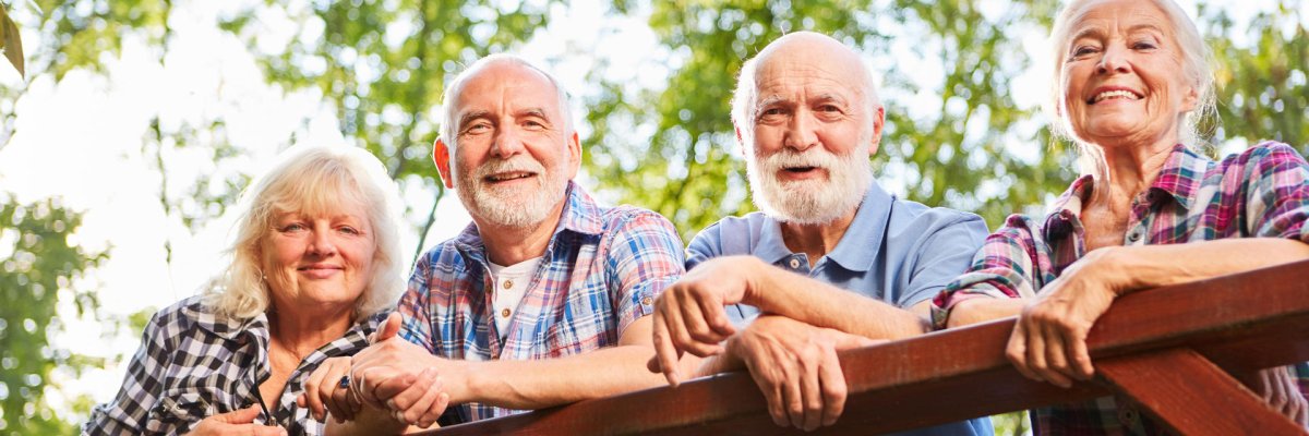 Seniors as friends are leaning against a bridge railing on a tour