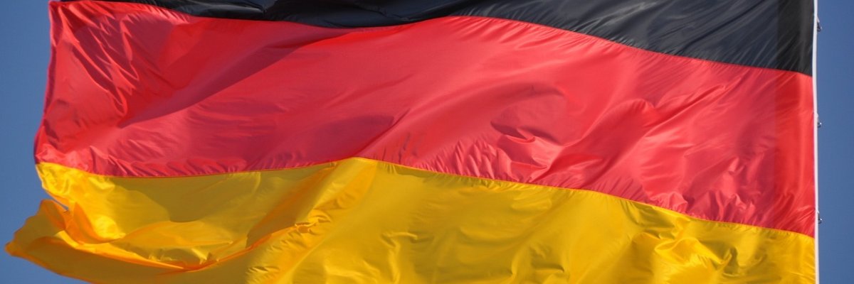 Eine Deutschlandflagge weht  vor blauem Himmel im Wind.