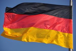 Eine Deutschlandflagge weht  vor blauem Himmel im Wind.