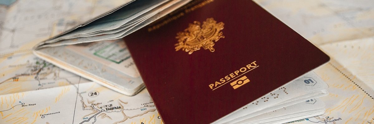 Das Bild zeigt einen aufgeschlagenen Reisepass, der auf einer Landkarte liegt.