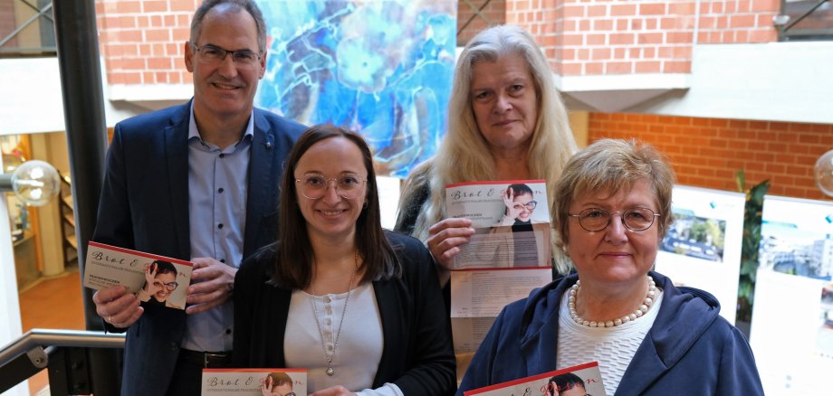 Drei Gleichstellungsbeauftragte im Landkreis Südliche Weinstraße und Landrat Dietmar Seefeldt halten das Programm der Frauenwochen Brot und Rosen 2024 in die Kamera.