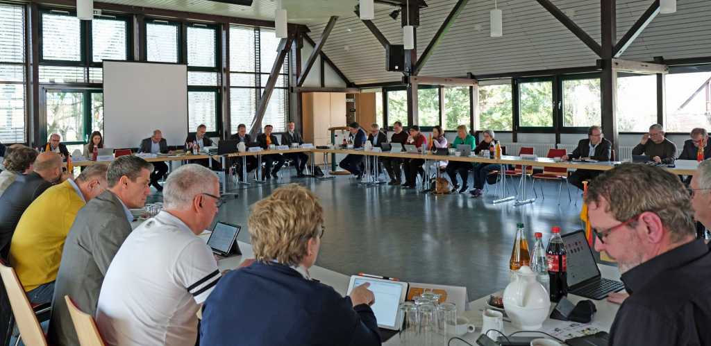 Mitglieder des Kreistags SÜW sitzen in großer Runde an Tischen.