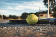 Sportstättenbeirat. Foto: Pixabay Nahaufnahme eines Tennisballs und zweier Tennisschläger, die auf dem Boden eines Tennisplatzes liegen. Der Hintergrund ist verschwommen.