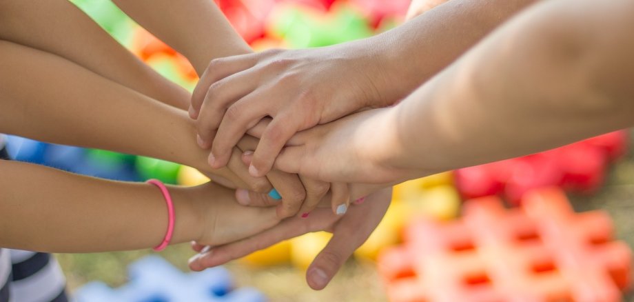 Kinderhände, die übereinander liegen.